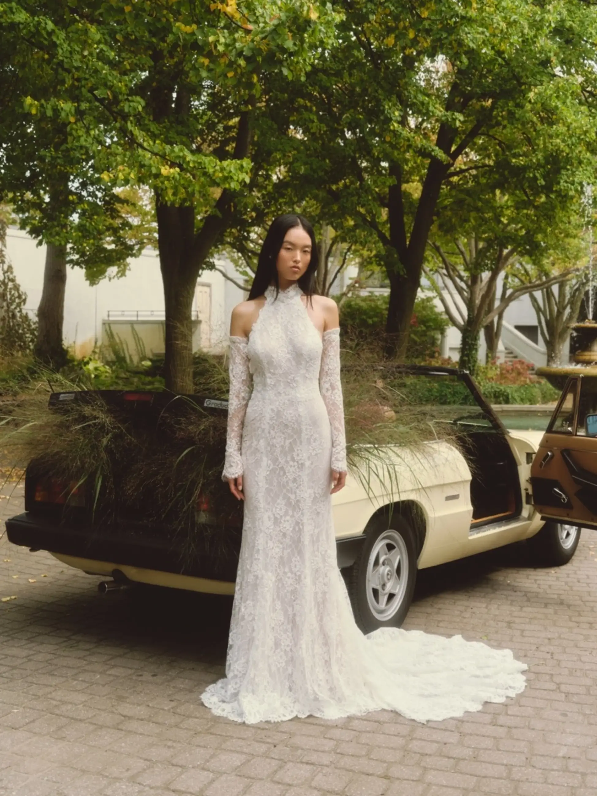 model is wearing a lace fit and flare wedding dress with cold shoulder cutouts