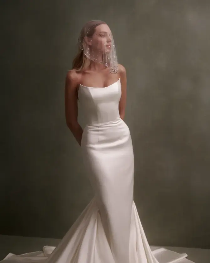 Model is wearing a satin mermaid bridal gown with a strapless scoop neckline
