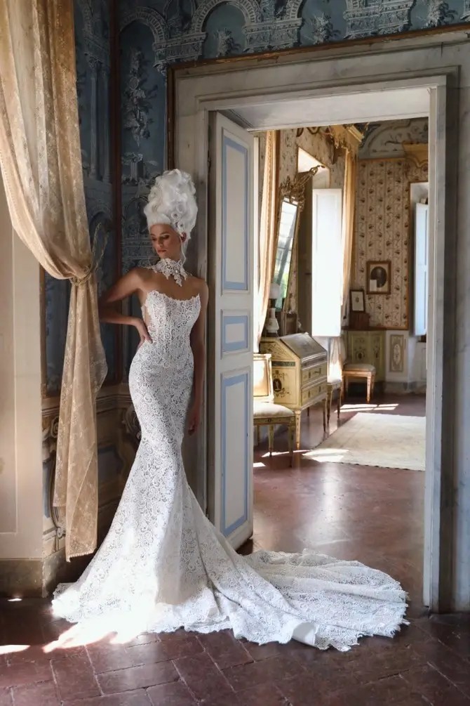 Model is wearing a strapless fit and flare lace wedding gown with a bold choker necklace