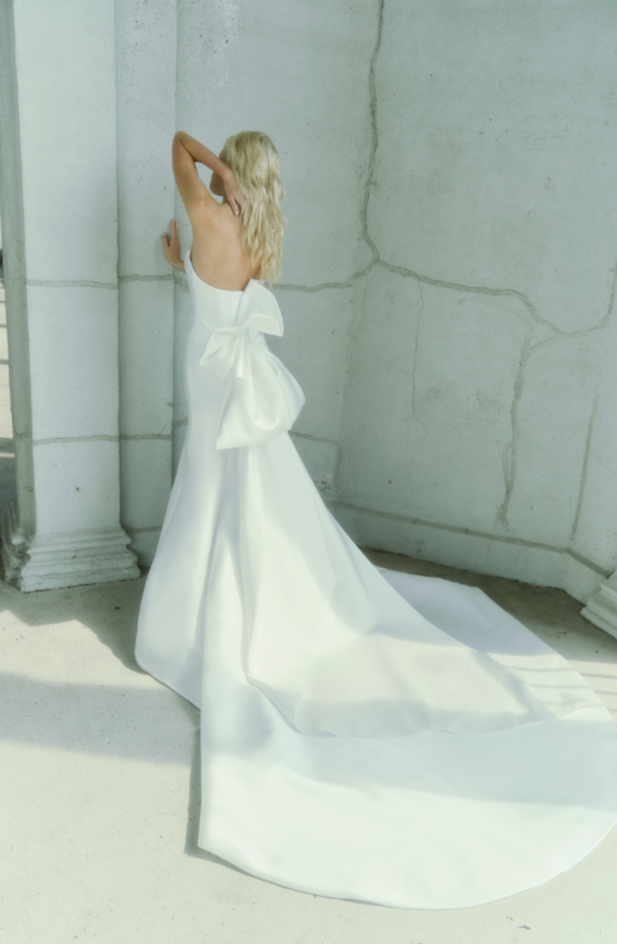 Model is wearing a fit and flare basque waist wedding dress with a cat eye neckline