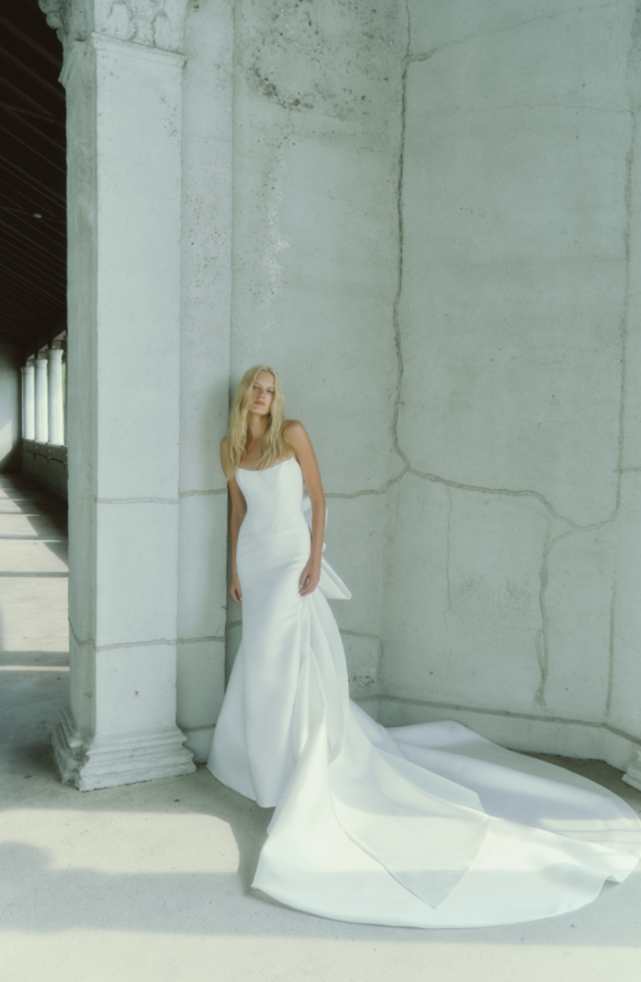 Model is wearing a fit and flare basque waist wedding dress with a cat eye neckline