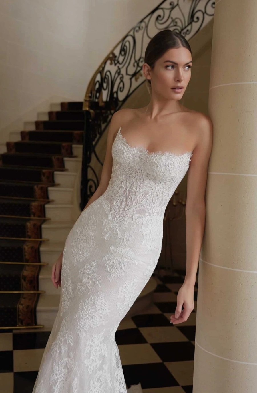 model is wearing a fitted strapless allover lace bridal gown
